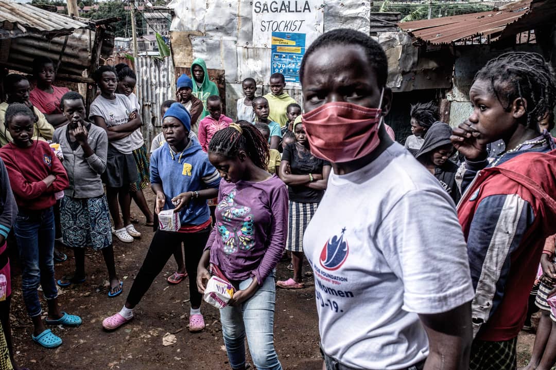 The photo shows a group of Kenyan teenagers holding sanitary pads they have received for free